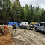 Travailleurs guidant le tuyau d’une pompe à béton pour une dalle de maison.